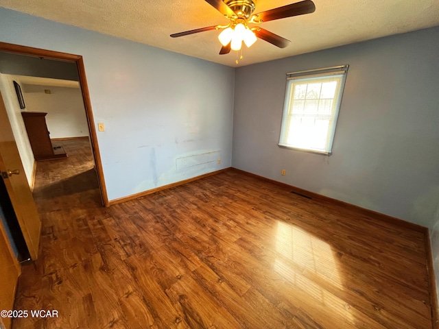 spare room with a textured ceiling, ceiling fan, wood finished floors, and baseboards