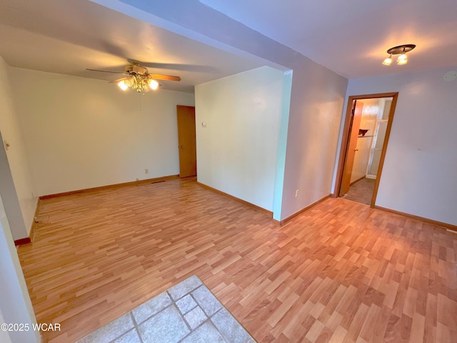 empty room with baseboards, ceiling fan, and light wood finished floors