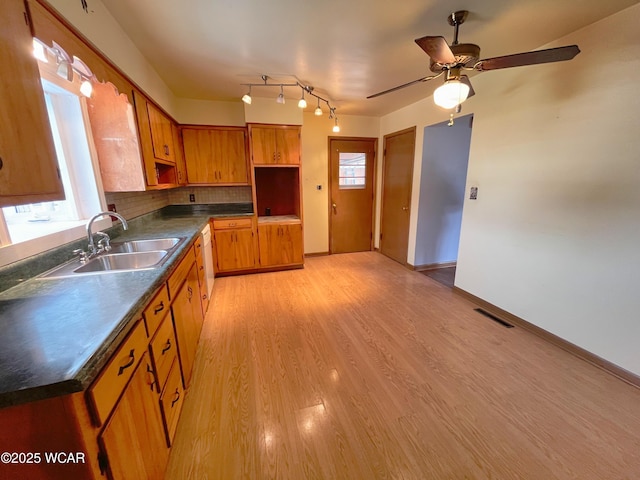 kitchen with light wood-type flooring, dark countertops, visible vents, and a sink