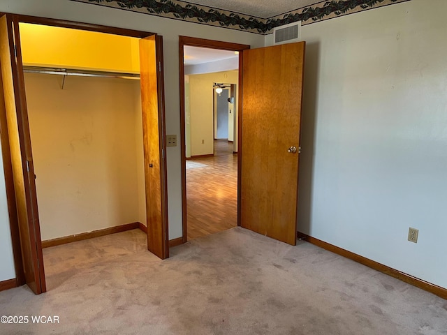 unfurnished bedroom with carpet floors, a closet, visible vents, and baseboards