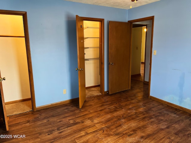 unfurnished bedroom with a closet, wood finished floors, and baseboards