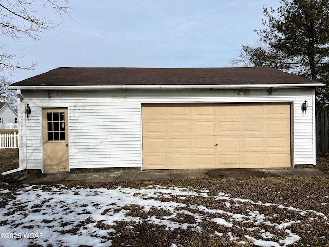 snow covered garage with a detached garage and fence