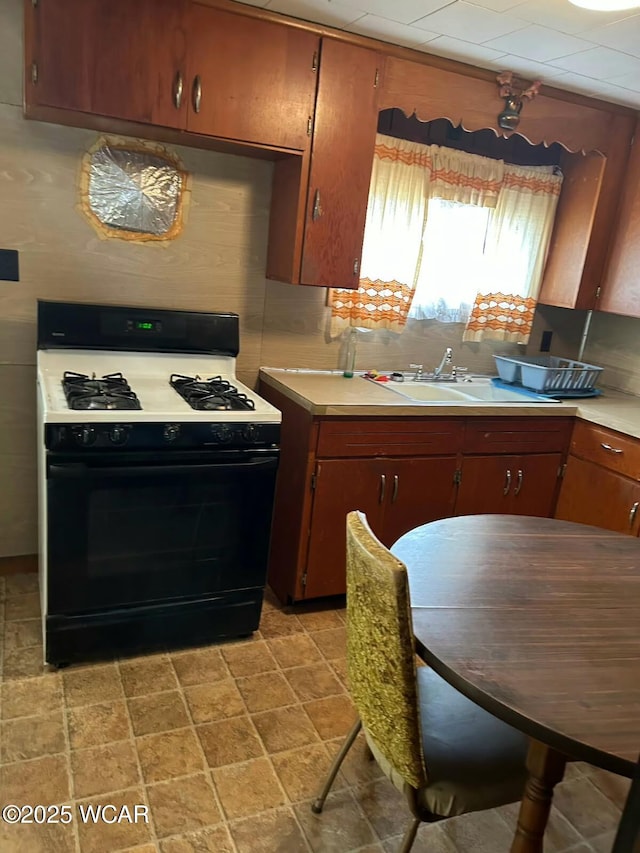 kitchen with tasteful backsplash, gas range oven, and sink