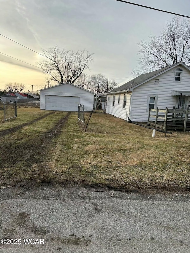 yard at dusk with a garage and an outbuilding