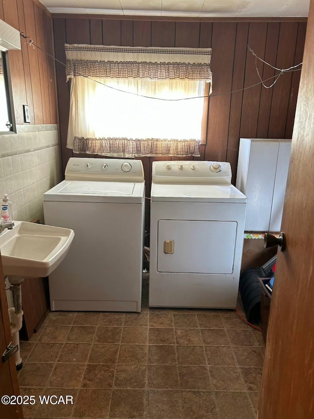 clothes washing area featuring independent washer and dryer and tile walls