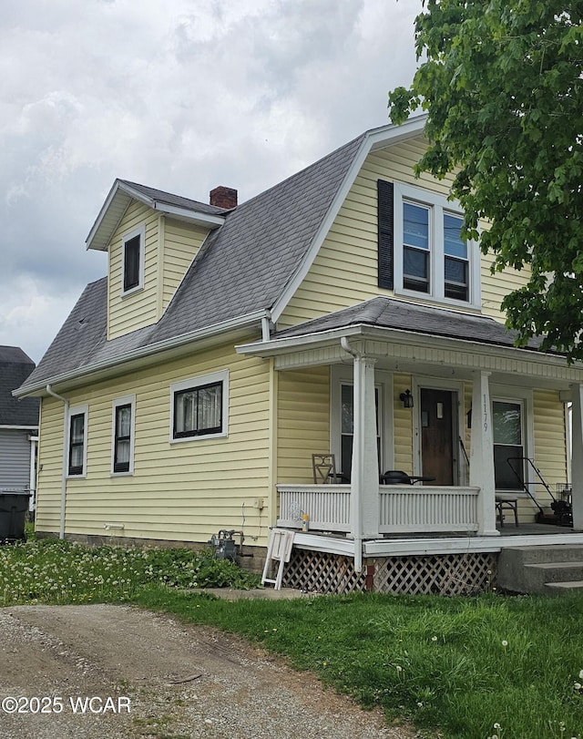 1179 W High St, Lima, OH 45805 - view of front facade with covered porch, a chimney, and roof with shingles