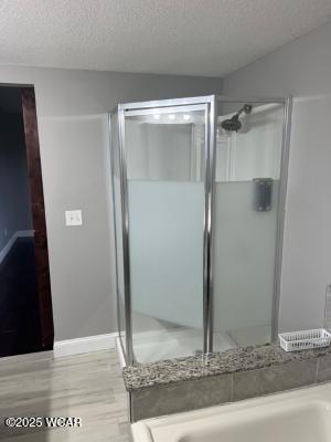 bathroom with a shower with shower door, hardwood / wood-style floors, and a textured ceiling