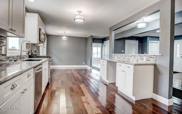 kitchen featuring pendant lighting, stainless steel appliances, light stone counters, and white cabinets