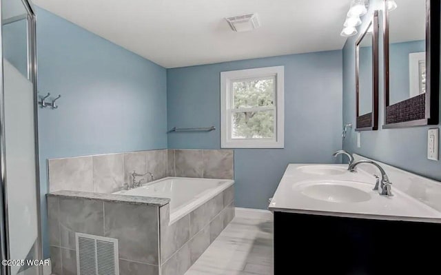 bathroom with tiled tub and vanity