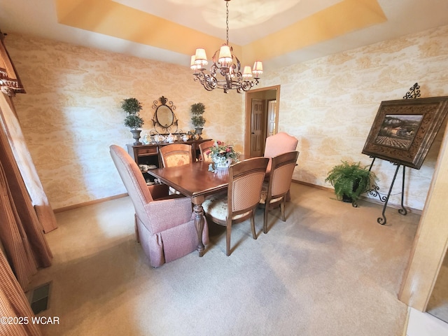 carpeted dining space featuring baseboards, wallpapered walls, a chandelier, visible vents, and a raised ceiling