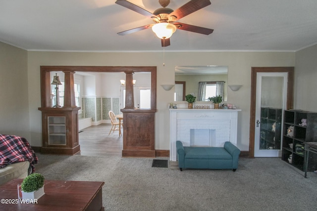 living room with carpet flooring, a fireplace, crown molding, and visible vents