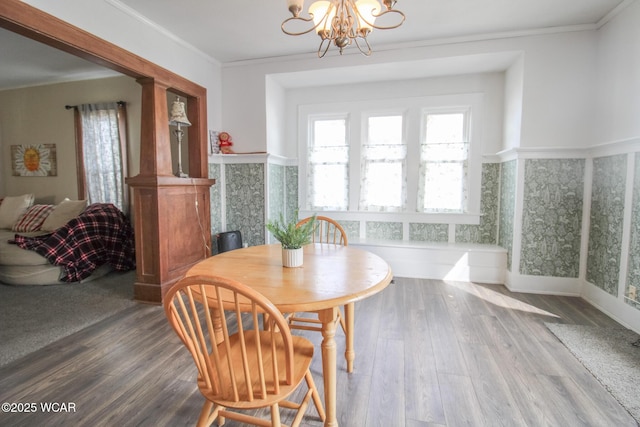 dining room with a chandelier, wood finished floors, ornamental molding, and a wainscoted wall