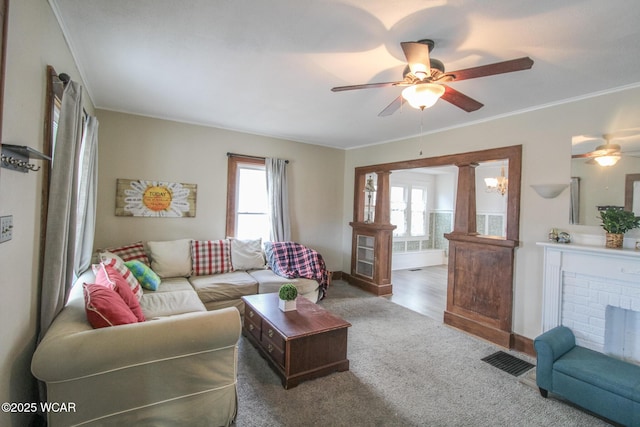 carpeted living room featuring visible vents, a fireplace, ornamental molding, and a ceiling fan