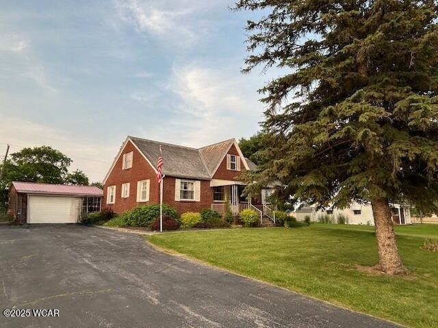 405 Walcot St, Willshire, OH 45898 - view of front of house with an outbuilding, a front yard, brick siding, and asphalt driveway