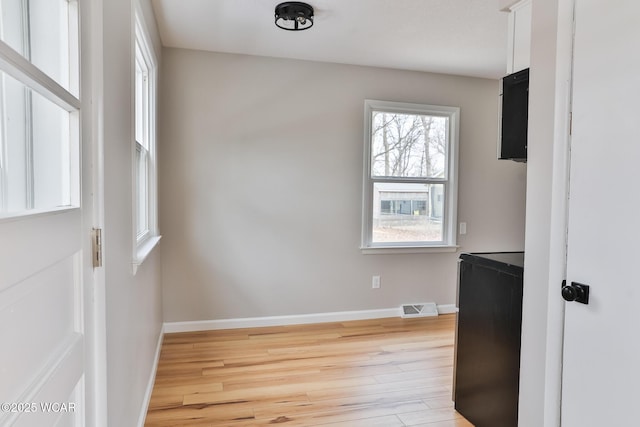 unfurnished room featuring light wood-type flooring, visible vents, and baseboards