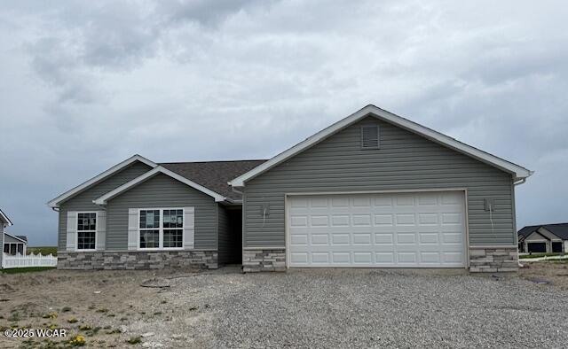ranch-style house with driveway, an attached garage, and stone siding