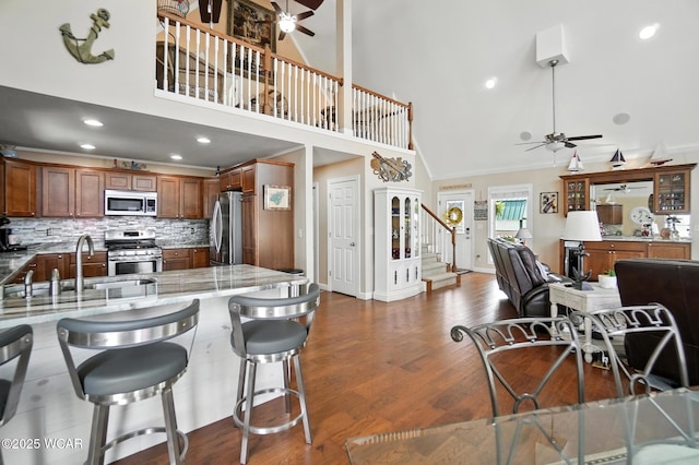 7407 Mingo Way, Russells Point, OH 43348 - kitchen featuring stainless steel appliances, ceiling fan, high vaulted ceiling, light stone countertops, and a breakfast bar area
