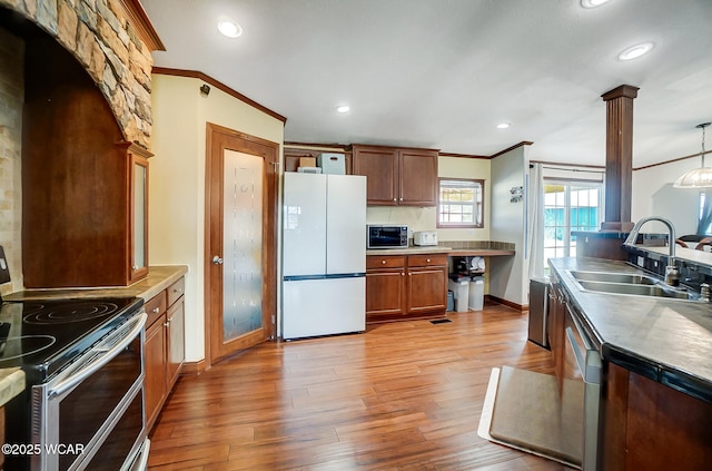 kitchen featuring ornate columns, pendant lighting, sink, stainless steel appliances, and crown molding