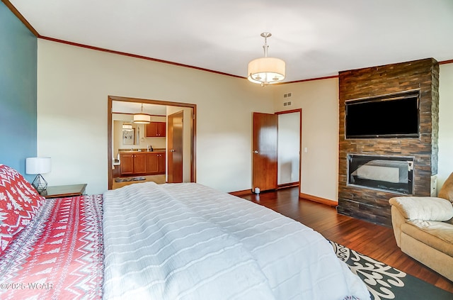 bedroom with ornamental molding, a large fireplace, and dark hardwood / wood-style flooring