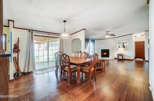 dining area featuring dark wood-type flooring, ornamental molding, and a wealth of natural light