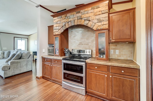 kitchen with decorative backsplash, ornamental molding, light hardwood / wood-style floors, and range with two ovens