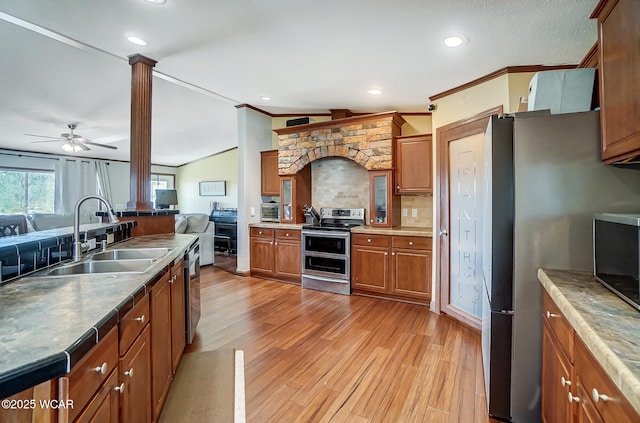 kitchen featuring sink, light hardwood / wood-style flooring, appliances with stainless steel finishes, decorative columns, and decorative backsplash