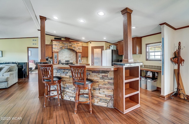 kitchen featuring lofted ceiling, light hardwood / wood-style flooring, fridge, kitchen peninsula, and decorative columns