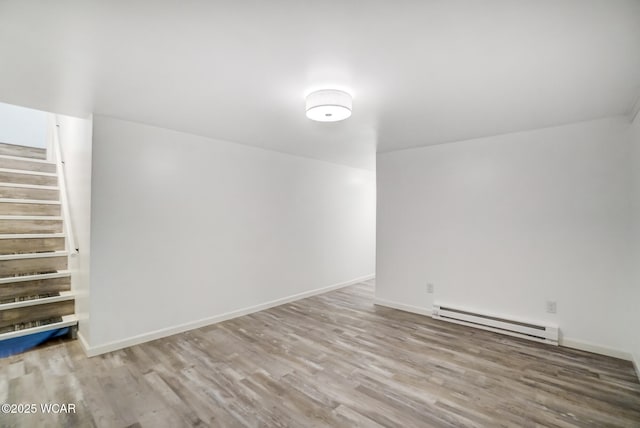 basement featuring baseboard heating and light hardwood / wood-style floors