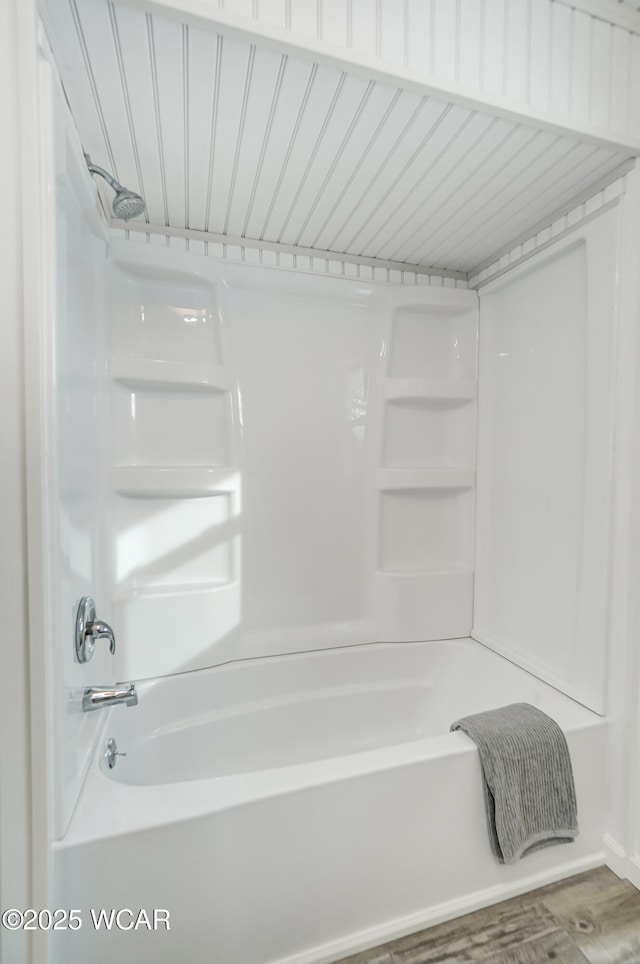 bathroom featuring hardwood / wood-style floors and washtub / shower combination