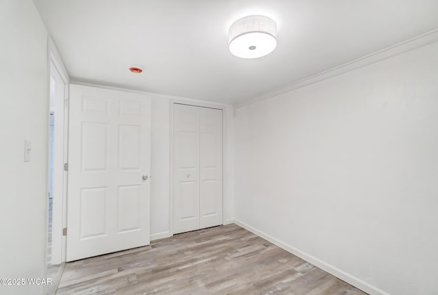 unfurnished bedroom with a closet, ornamental molding, and light hardwood / wood-style floors