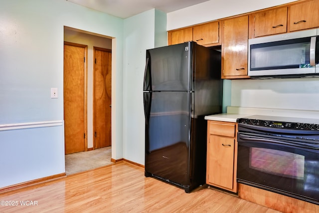 4940 Stewart Rd, Lima, OH 45801 - kitchen featuring stainless steel microwave, freestanding refrigerator, range with electric cooktop, light wood-style floors, and light countertops