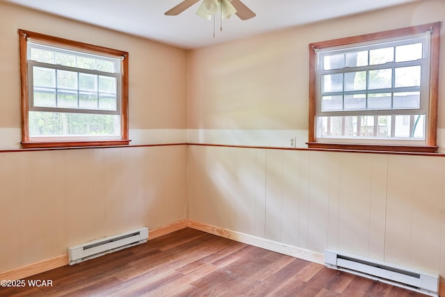 4940 Stewart Rd, Lima, OH 45801 - empty room featuring a baseboard radiator, plenty of natural light, wood finished floors, and a wainscoted wall