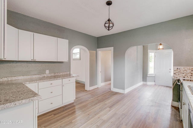 1157 W High St, Lima, OH 45805 - kitchen with arched walkways, white cabinetry, light wood-style flooring, and pendant lighting