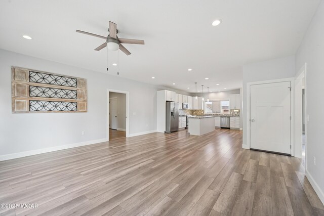6856 Creekview Ct, Huntsville, OH 43324 - kitchen with light wood-type flooring, backsplash, a center island, appliances with stainless steel finishes, and white cabinets