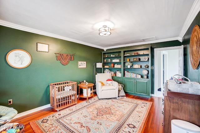 bedroom with hardwood / wood-style floors, crown molding, and a crib