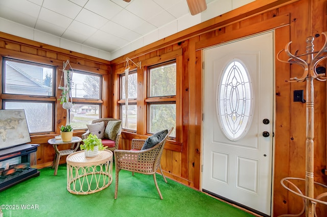 foyer entrance with wooden walls and carpet