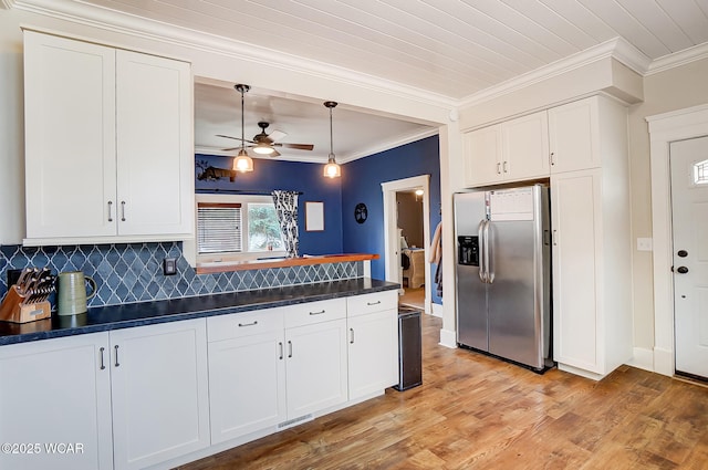 kitchen with hanging light fixtures, ornamental molding, white cabinets, and stainless steel fridge