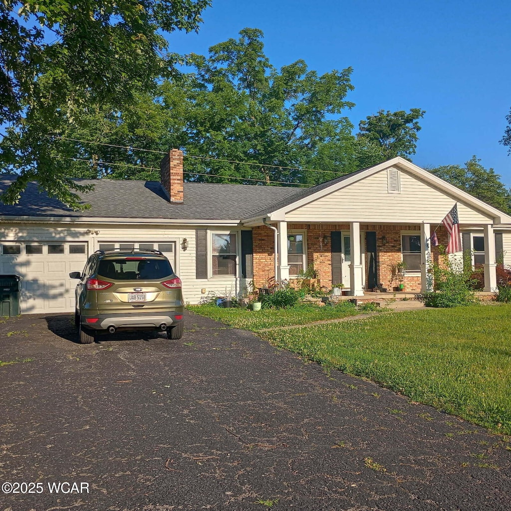 1457 Ivy Dr, Lima, OH 45807 - view of front of property with driveway, an attached garage, a chimney, a front lawn, and brick siding
