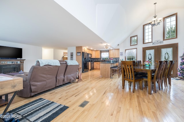 16949 Township Road 39, Belle Center, OH 43310 - dining room with light wood-type flooring, a chandelier, a fireplace, and high vaulted ceiling