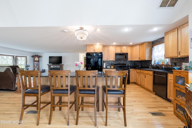 16949 Township Road 39, Belle Center, OH 43310 - kitchen with black appliances, light wood-type flooring, a sink, dark countertops, and tasteful backsplash