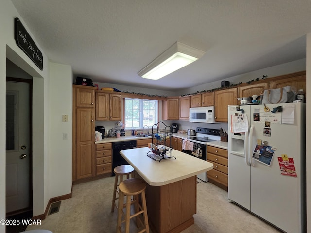 1919 Jared Pl, Lima, OH 45805 - kitchen featuring white appliances, a sink, light countertops, a kitchen island, and brown cabinetry