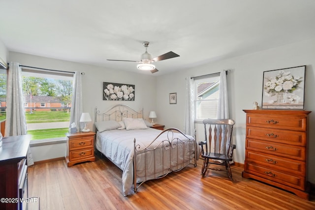 bedroom with baseboards, multiple windows, light wood finished floors, and ceiling fan