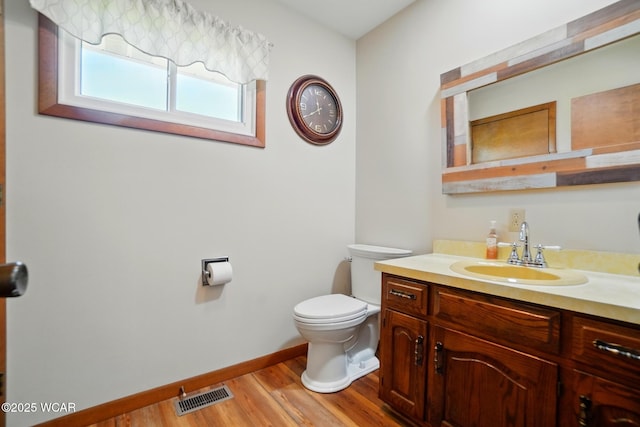 bathroom featuring toilet, baseboards, visible vents, vanity, and wood finished floors