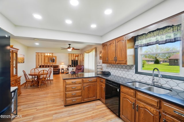 kitchen featuring light wood-style flooring, brown cabinetry, black dishwasher, a sink, and a peninsula