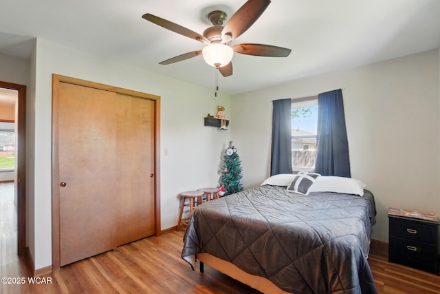 bedroom with a ceiling fan, baseboards, a closet, and wood finished floors