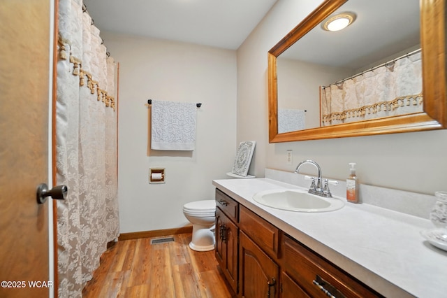 full bathroom with toilet, wood finished floors, vanity, visible vents, and baseboards