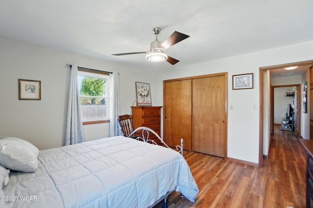 bedroom with baseboards, a closet, a ceiling fan, and wood finished floors
