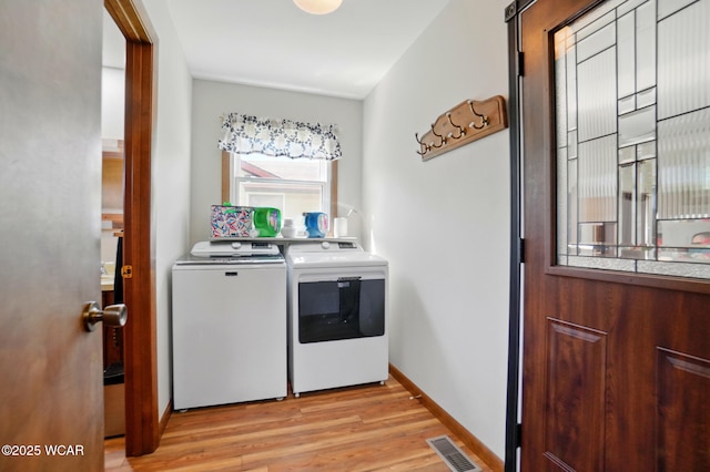 clothes washing area with baseboards, visible vents, washer and clothes dryer, light wood-style floors, and laundry area
