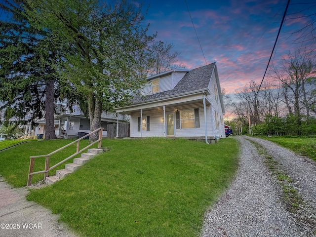bungalow with a lawn, covered porch, driveway, and roof with shingles