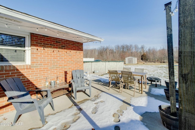 snow covered patio with a storage unit